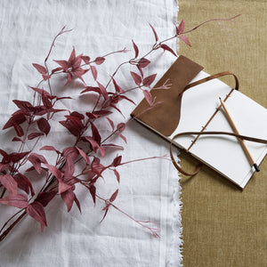 Ornamental burgundy leaf decor arranged alongside a blank notebook and pencil on a table